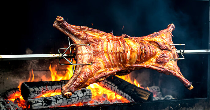 Mexico &ndash; Cabrito al Pastor (Whole Baby Goat). a whole baby goat splayed on a metal cross spit, rotating before a massive mesquite wood fire 