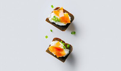 Two flying smoked salmon canapes on pumpernickel bread.