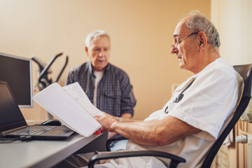 Cardiologist consulting with a senior male patient during a detailed heart examination in a medical clinic. © djoronimo
