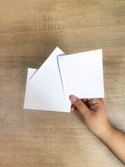 Obraz premium Blank slate. Hand holding paper, ready for ideas on a wooden surface background. Copy space.