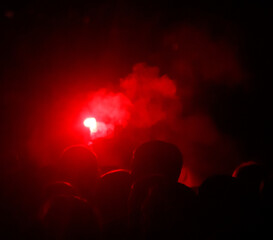 A group of people are gathered in a dark room with a red light in the center