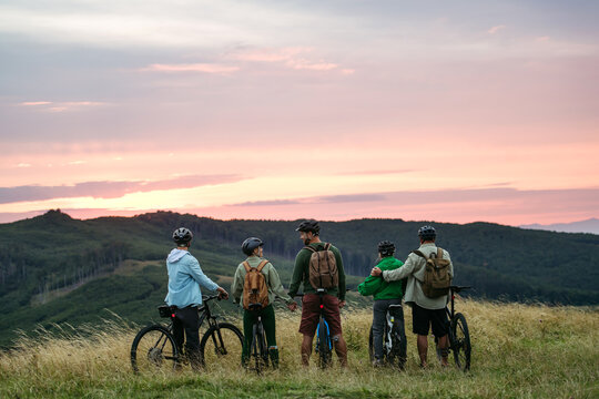 Family standing with bicycles at sunset in mountains. Cycling trip during autumn day.