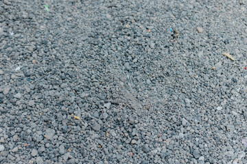 A close-up view of small gravel and crushed stones scattered on the ground. The textured surface shows irregular shapes and natural tones, often used in construction, roadwork, or landscaping.