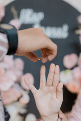 A close-up photo of two hands holding a pair of gold wedding rings together. One hand belongs to a man and the other to a woman, symbolizing love, unity, and commitment.