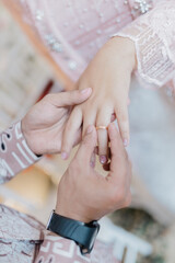 A close-up photo of two hands holding a pair of gold wedding rings together. One hand belongs to a man and the other to a woman, symbolizing love, unity, and commitment.