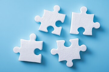 Obraz premium Four white puzzle pieces on a light blue surface