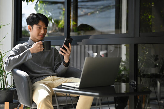 Relaxed digital lifestyle with a young man multitasking between mobile and laptop in a sunny outdoor workspace