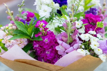 Wrapped flower bouquet made of mixed spring flowers. Beautiful pink, white and blue fresh flowers arrangement. Birthday bouquet with larkspur and matthiola stock.