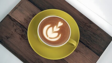 Delicate Latte Art in Yellow Cup on Wooden Board A Coffee Lover's Delight