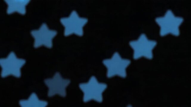 Abstract small cute blue stars rotating and flowing on black background, seamless loop. Animation. Five pointed stars in diagonal rows moving and spinning.