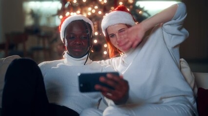 Celebrate Christmas and new year, portrait of african man and caucasian lady. Loving couple chatting online with friends and family by video conference in modern smartphone, happy faces and smiles - Powered by Adobe