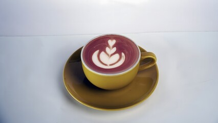 Delicious and decorative latte art in a yellow cup with a saucer