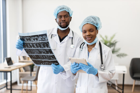 Doctors, male and female, analyzing diagnostic imaging results in hospital office teamwork environment.