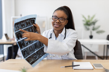 Young adult female doctor analyzing radiographic images in clinical setting, showcasing professionalism. Scene depicts medical expertise, technology usage, and patient care in healthcare workplace