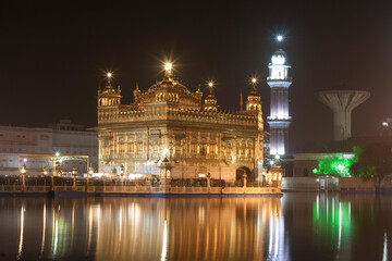 Fototapeta premium Golden Temple in Midnight with Smooth Reflection in water.