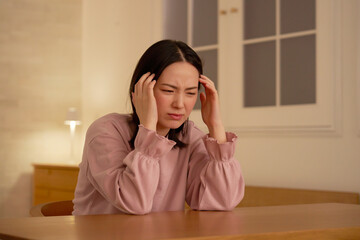 夜に自宅で頭痛がする女性