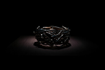 Fototapeta premium Close up of a dark metal ring with an intricate interwoven design on a dark reflective surface