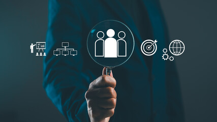 A hand holds a magnifying glass over icons representing teamwork, goals, and global connections, conveying a focus on analysis and collaboration in business.