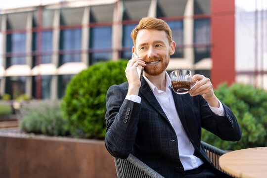 Bearded worker holding coffee cup during mobile conversation