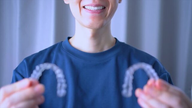 Clear Dental Aligners or braces. Orthodontic mouthpiece that a smiling person held in hand. Slow motion video.