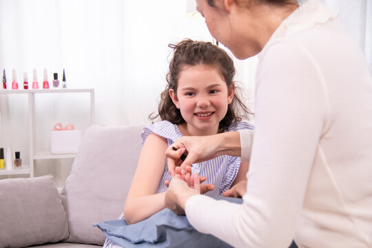 Mother painting daughter’s nails while sitting together on sofa, inspiration content creator kid, family moment healthcare, skincare treatment, daily lifestyle wellness and parenting connection story - Powered by Adobe