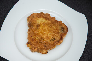 The image shows a piece of breaded and fried meat, which is commonly known as schnitzel or a breaded cutlet. 
Schnitzel is a dish of thin, boneless meat that is pounded, coated with flour, eggs, and b