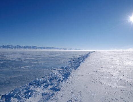 Vast expanse of frozen lake, bright sun, icy edge