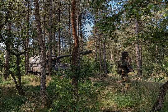 Artillery howitzer with infantry support conducting woodland tactical exercise