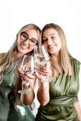 Vertical close-up of two women with glasses, holiday cheers in studio