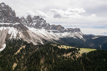 Sharp peaks of the Dolomites mountains rising above forest in Italy. Aerial view