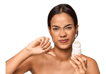 Filipino woman holds deodorant in studio showing a dislike gesture, thumbs down. Disagreement concept.