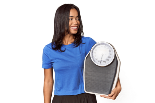 Filipino woman with scale in studio looks aside smiling, cheerful and pleasant.