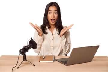 Woman records podcast with laptop surprised and shocked.