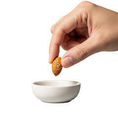 Adult hand with warm skin picking up a glistening roasted almond from a matte ceramic bowl, isolated on a transparent background with soft studio light and subtle bokeh, concept of mindful consumption