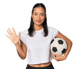 Young Filipino woman with soccer ball smiling cheerful showing number five with fingers.