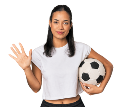 Young Filipino woman with soccer ball smiling cheerful showing number five with fingers.