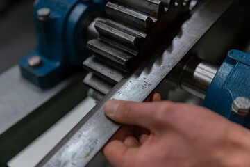 Worker measuring machined gear component with precision measuring tools