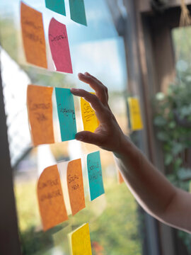 Close-up of hand holding sticky note during strategic planning and idea organization