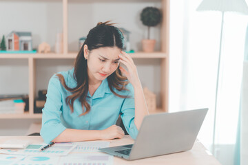 Obraz premium Asian businesswoman dealing with stress and headache feels depressed from low sales, bad economy, business