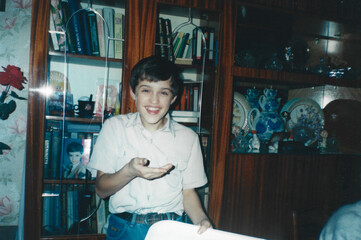 Twelve-year-old boy laughs in surprise looking at camera, photo taken with flash in home interior, captured in analog photography style from mid-1990s Ukraine