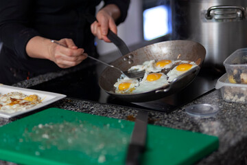 Chef cooking several eggs simultaneously in large pan during breakfast preparation