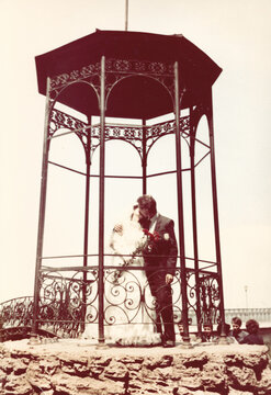 Analog wedding photo of a couple under an arch in Odessa, mid-1980s Ukrainian SSR with classic bridal attire and vintage atmosphere