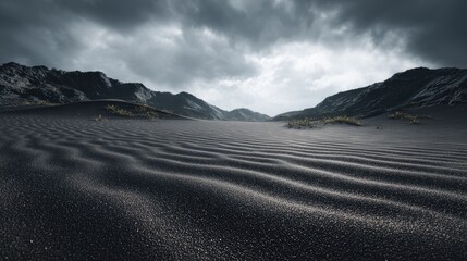 Dark sand dunes stretch towards mountains under stormy sky