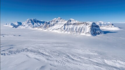 Obraz premium A breathtaking snowy mountain range stretches under clear blue skies, showcasing pristine peaks and vast alpine beauty.