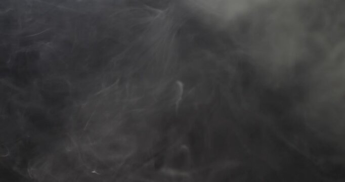 Gray smoke on a black background. Smoky air in the room. Cigarette smoke slowly rises to the top. Fire with smoke.