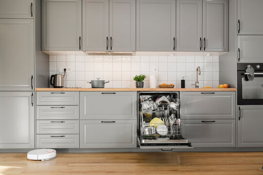 Dishes inside dishwasher and robot vacuum in kitchen