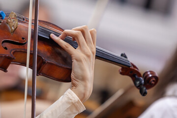Hand of a girl playing the violin in an orchestra