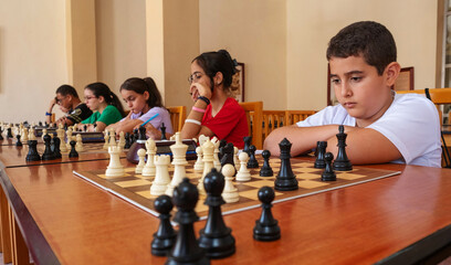 Children focusing on a simultaneous chess game in progress