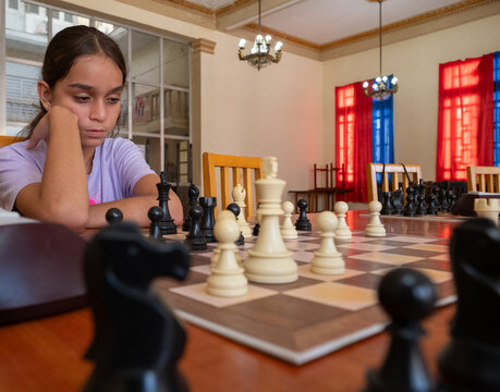 Young girl deep in thought over a chessboard