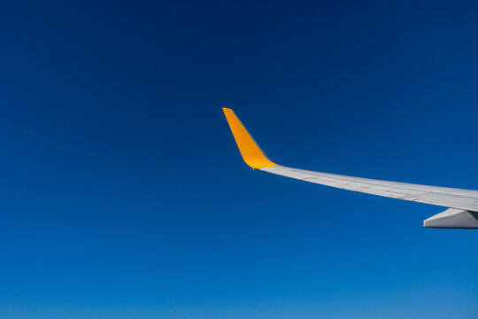 Airplane wing against clear blue sky